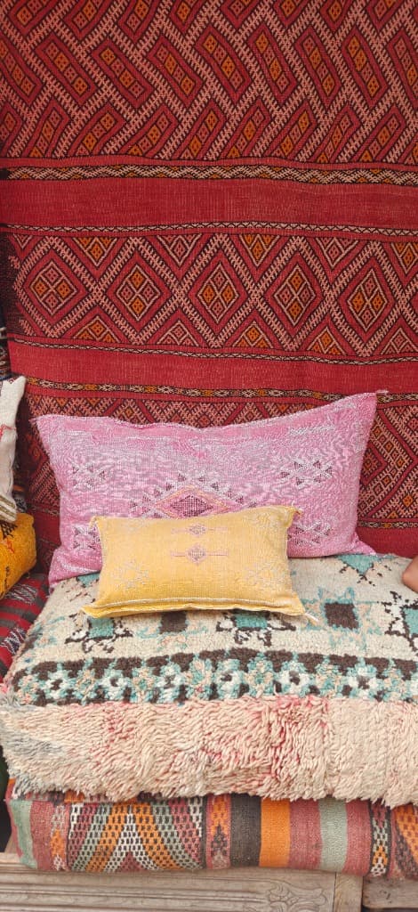 Pink and yellow cushions on a traditional rug